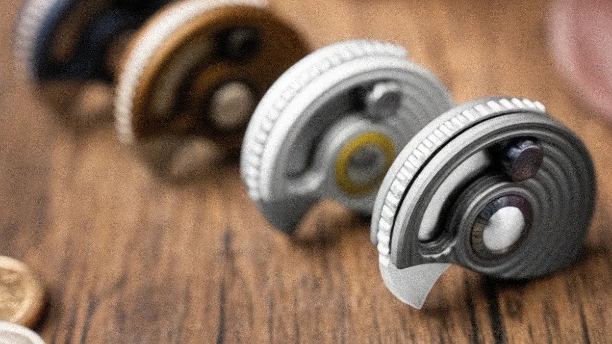 Four mechanical watch escapement parts arranged in a row on a wooden surface, with the closest one in sharp focus.