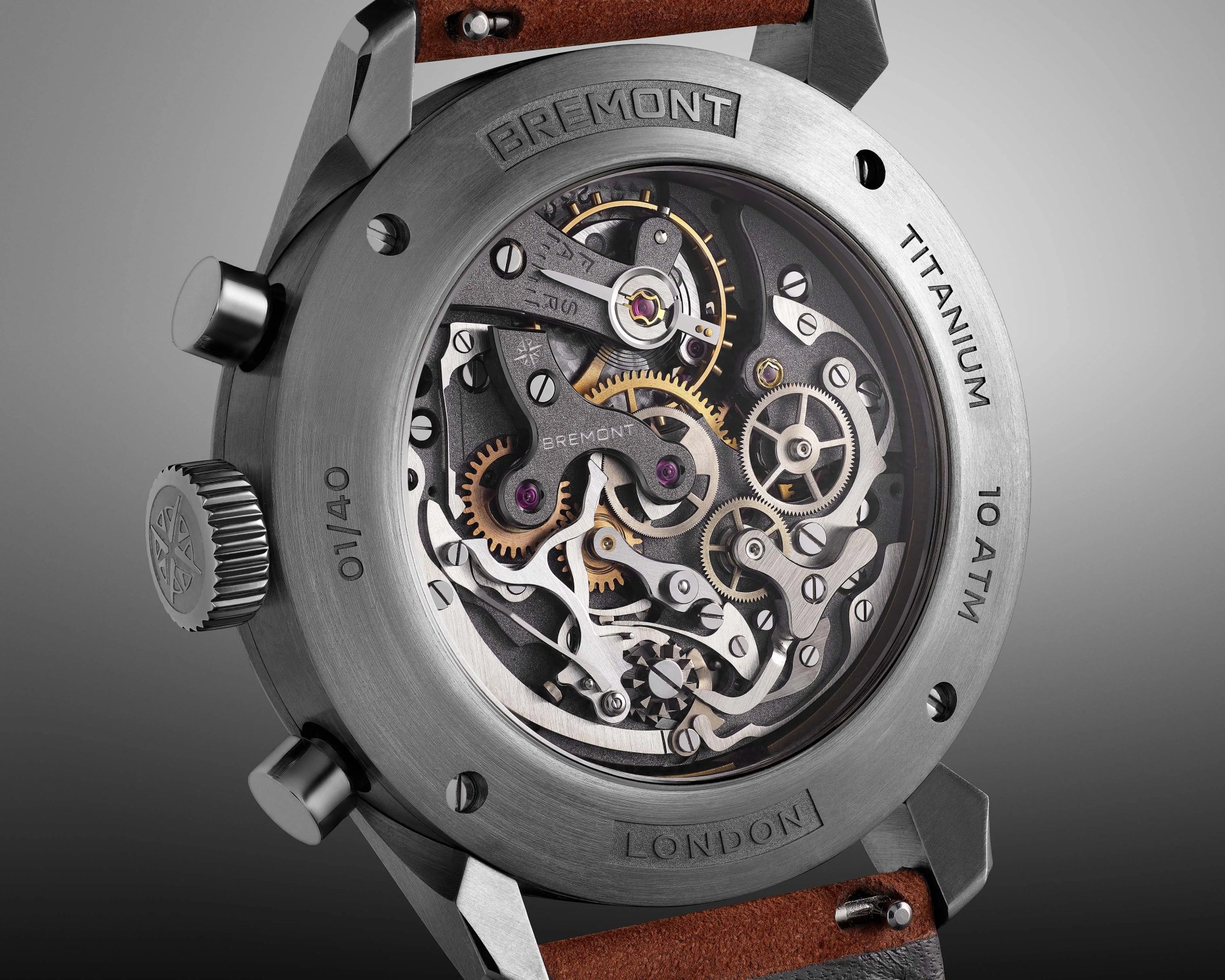 Close-up of the back of a Bremont titanium watch showing intricate mechanical gears and a brown leather strap.