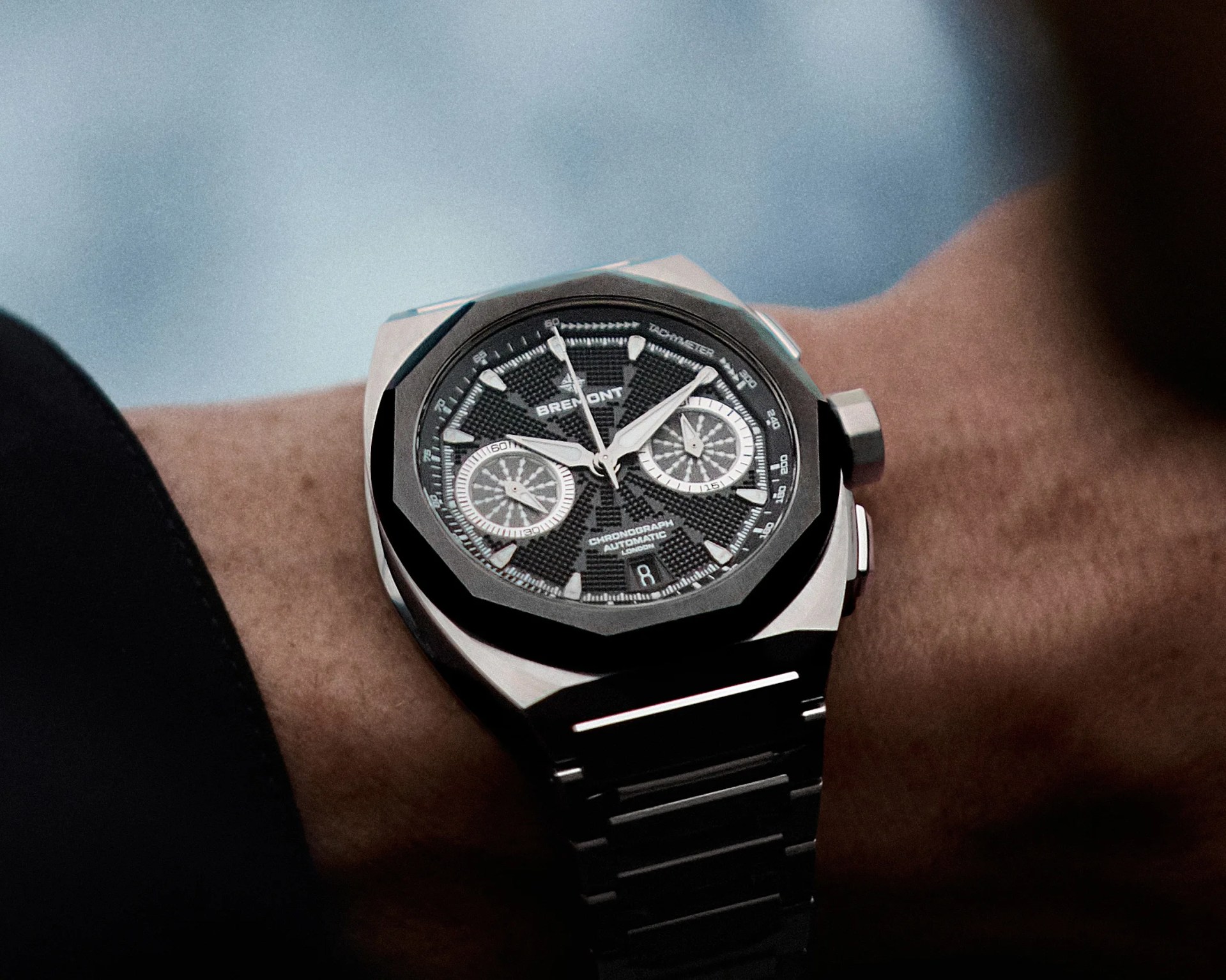 Black textured dial Bremont chronograph watch with silver subdials and stainless steel bracelet on a wrist.