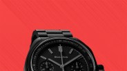 Black Bulova chronograph watch with tachymeter bezel against a red textured background.