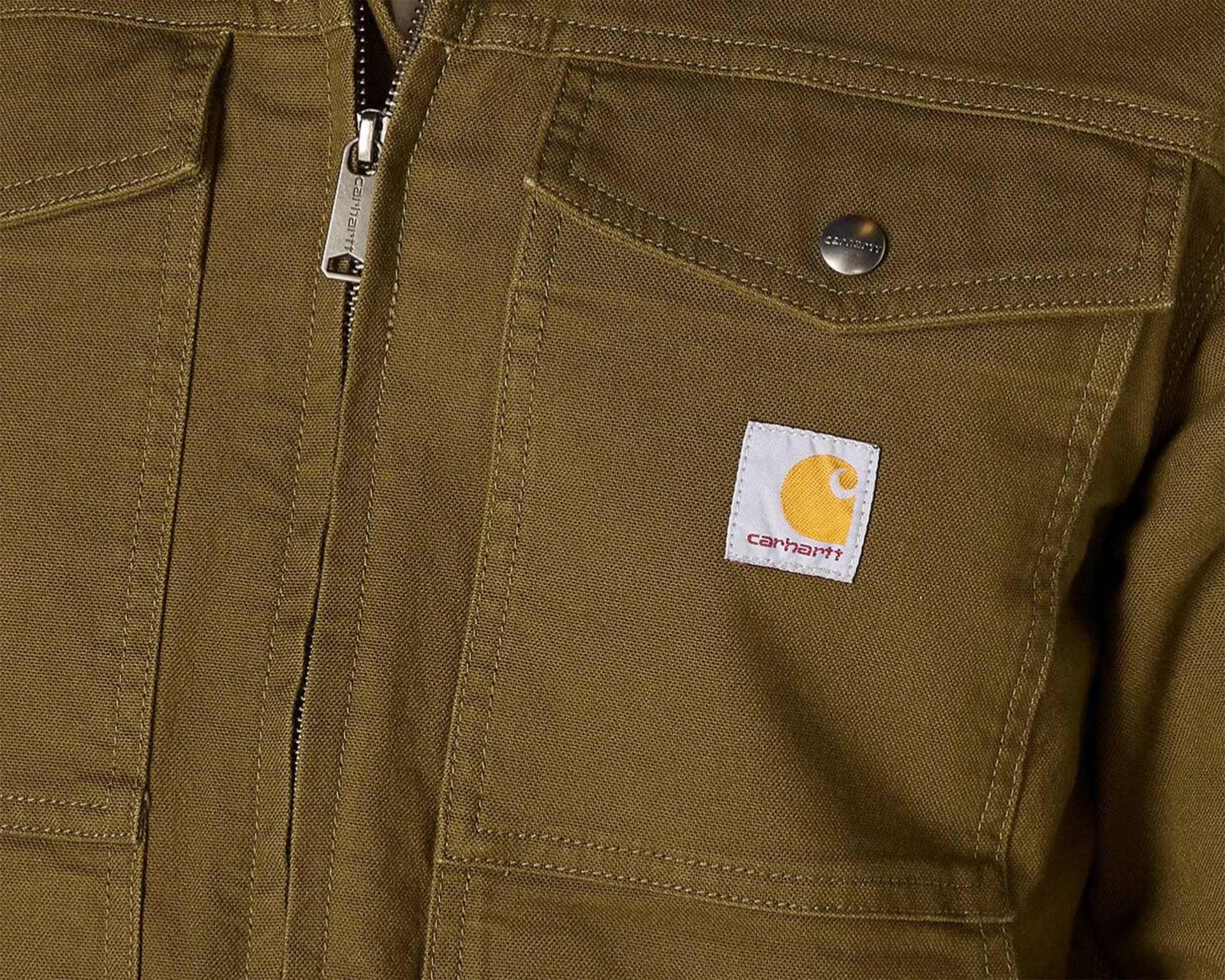 Close-up of a brown Carhartt jacket pocket with a metal snap button and a zipper pull.