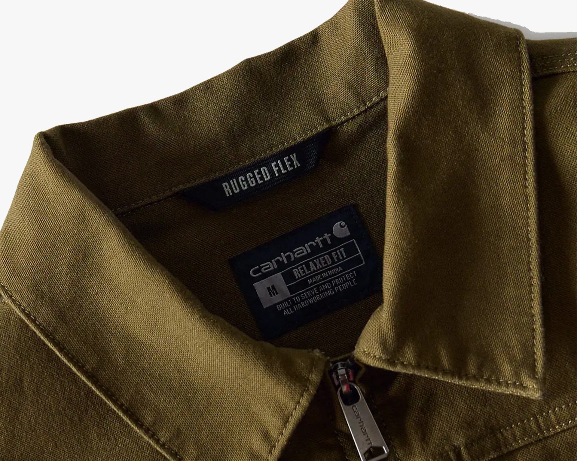 Close-up of an olive-green Carhartt jacket collar with "Rugged Flex" and "Relaxed Fit" labels and a metal zipper pull.
