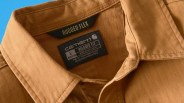Close-up of a brown Carhartt Rugged Flex shirt collar with black size and brand labels.