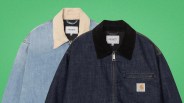 Two Carhartt denim jackets, one light blue with a beige collar and one dark blue with a black collar and front zipper pocket.