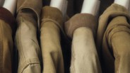Close-up of several earth-toned jackets hanging on white hangers.