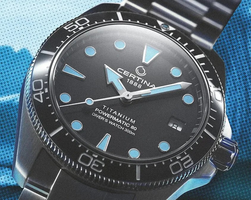 Close-up of a Certina 1888 titanium diver's watch with blue hour markers and a black bezel on a metal bracelet.