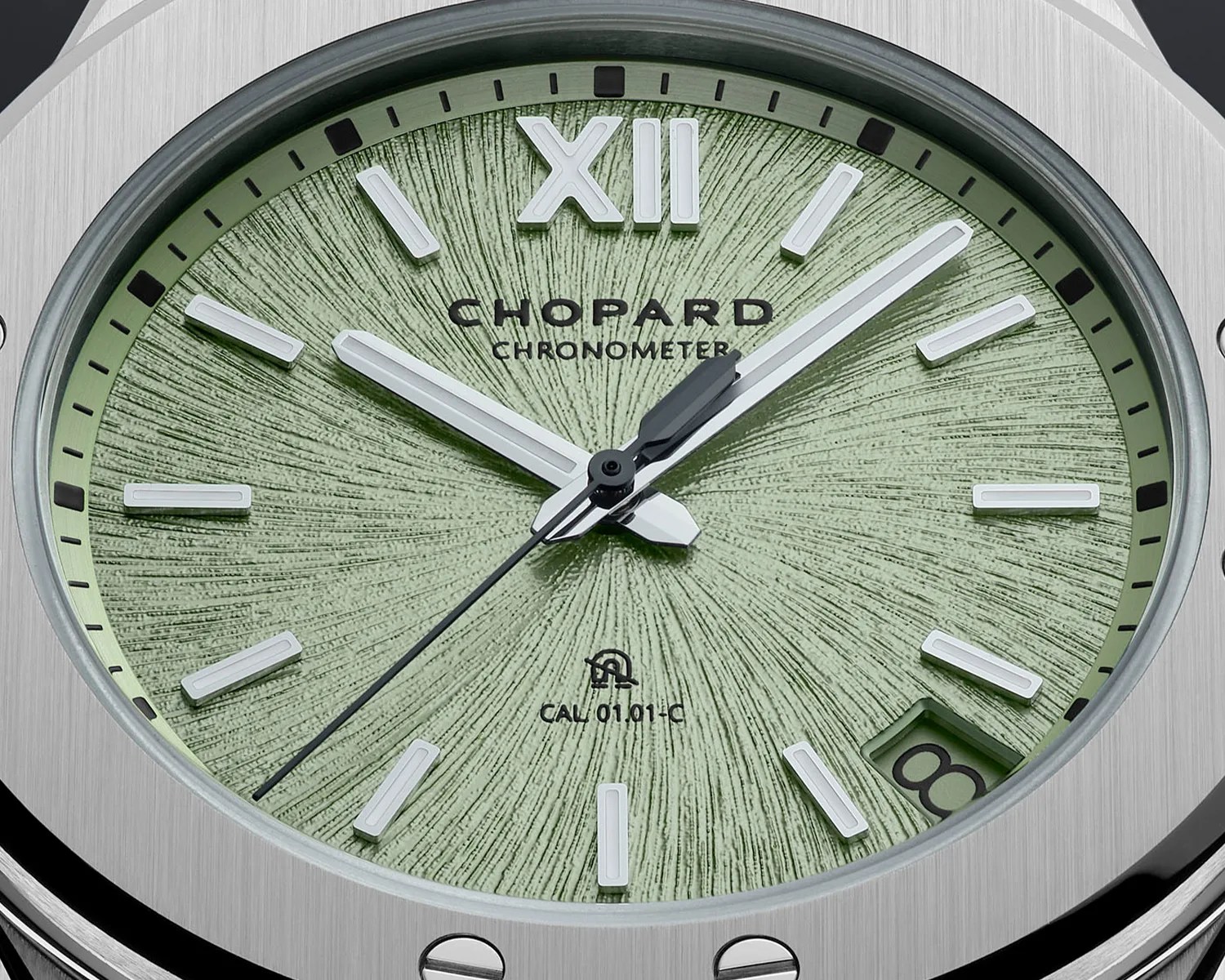 Close-up of a Chopard chronometer watch with a textured green dial, silver hour markers, and a date window at 4 o'clock.
