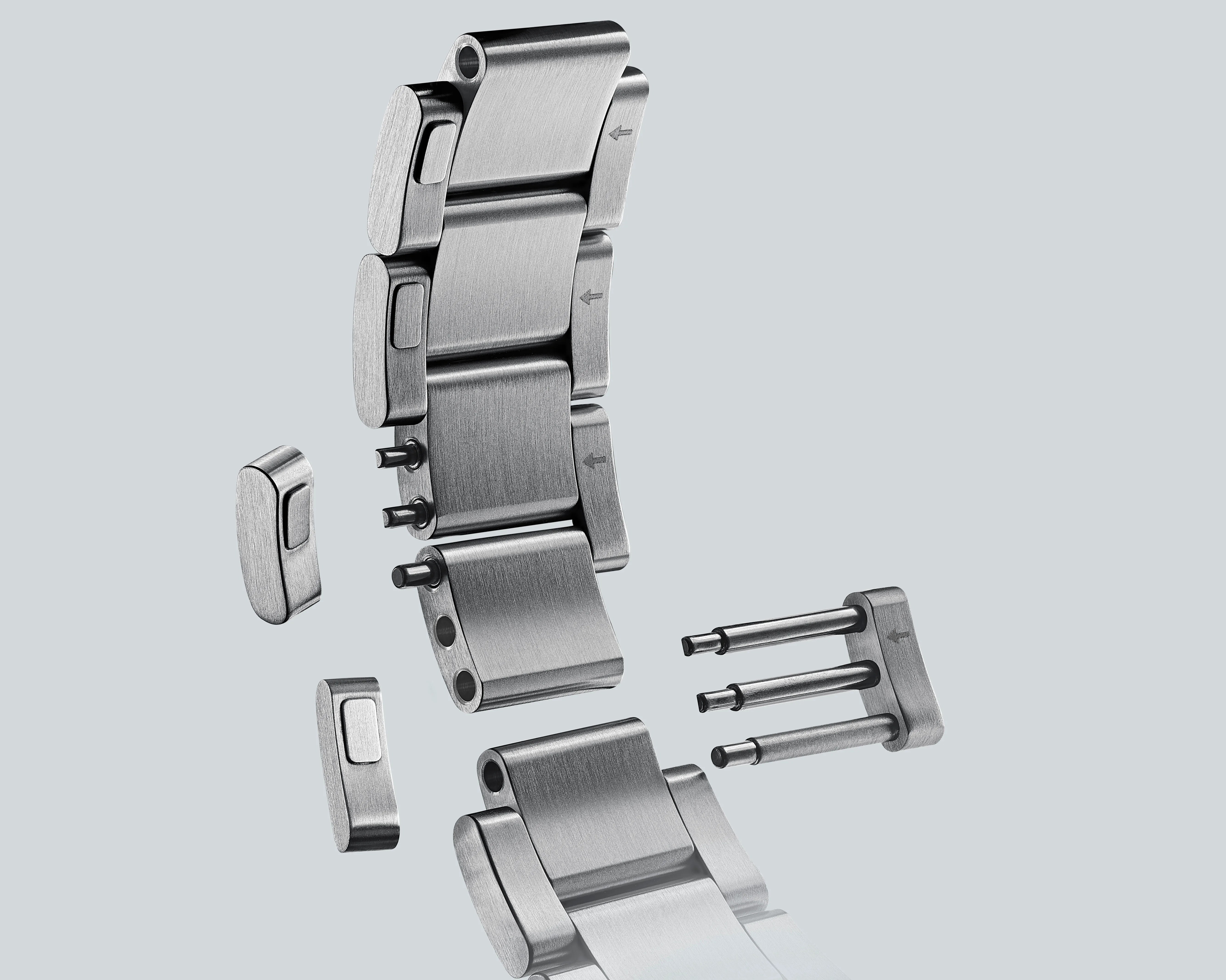 Brushed stainless steel watch band links and pins disassembled on a light gray background.