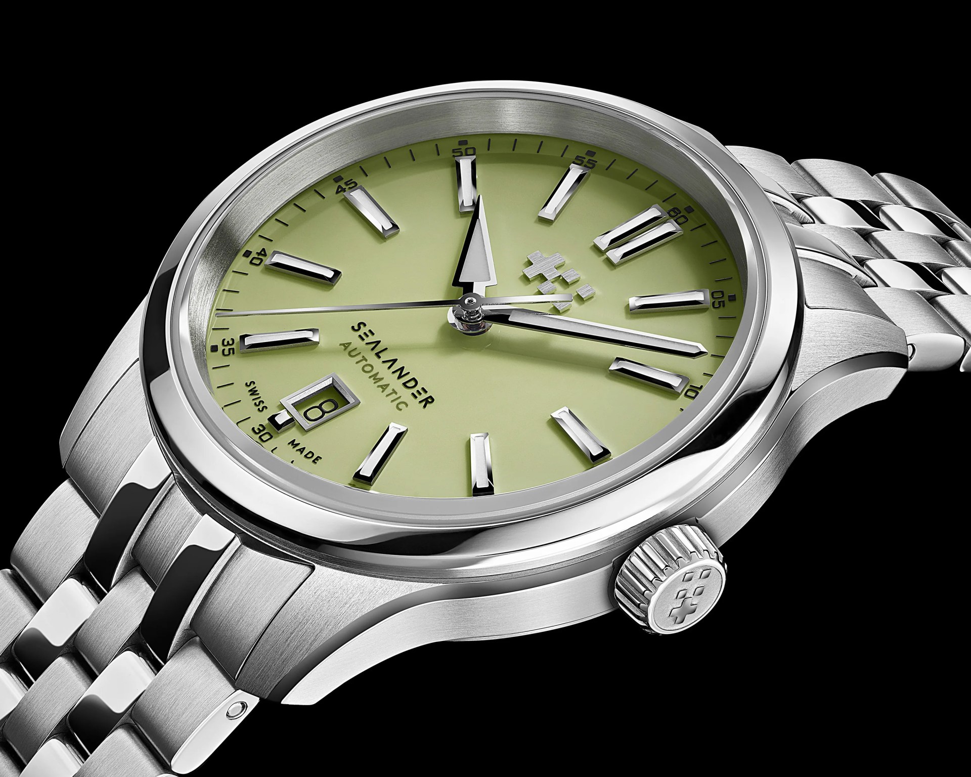 Close-up of a stainless steel wristwatch with a light green dial, silver hour markers, and a date window at 6 o'clock.