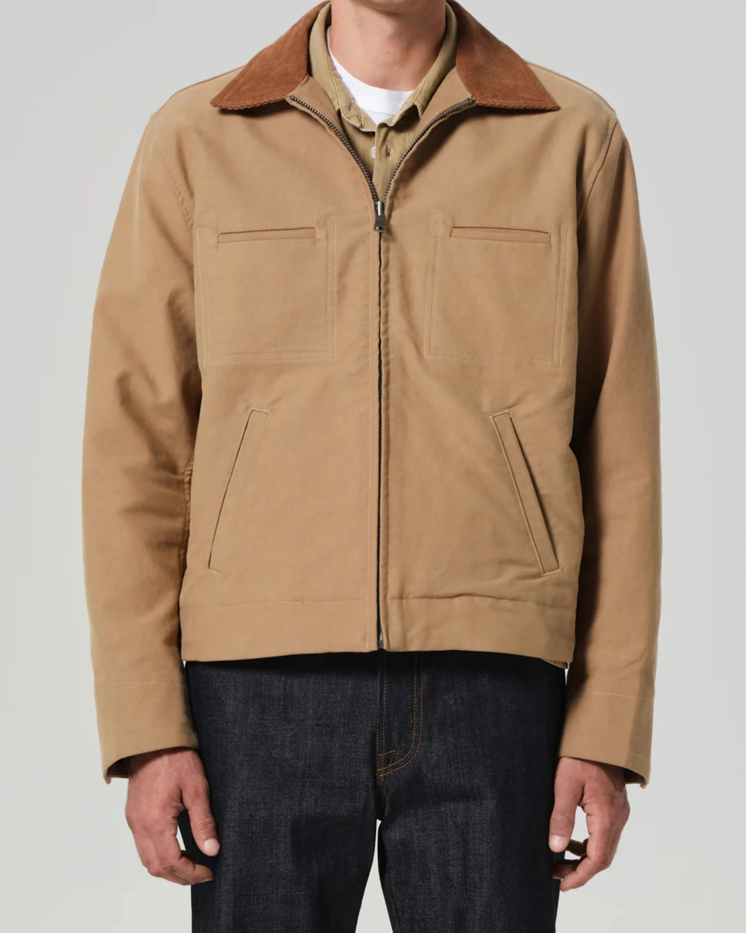 Tan zip-up jacket with brown corduroy collar and four front pockets worn over layered shirts.