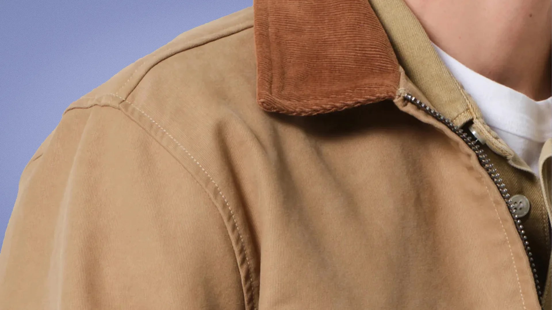 Close-up of a tan jacket with a brown corduroy collar and a visible zipper over a white shirt.
