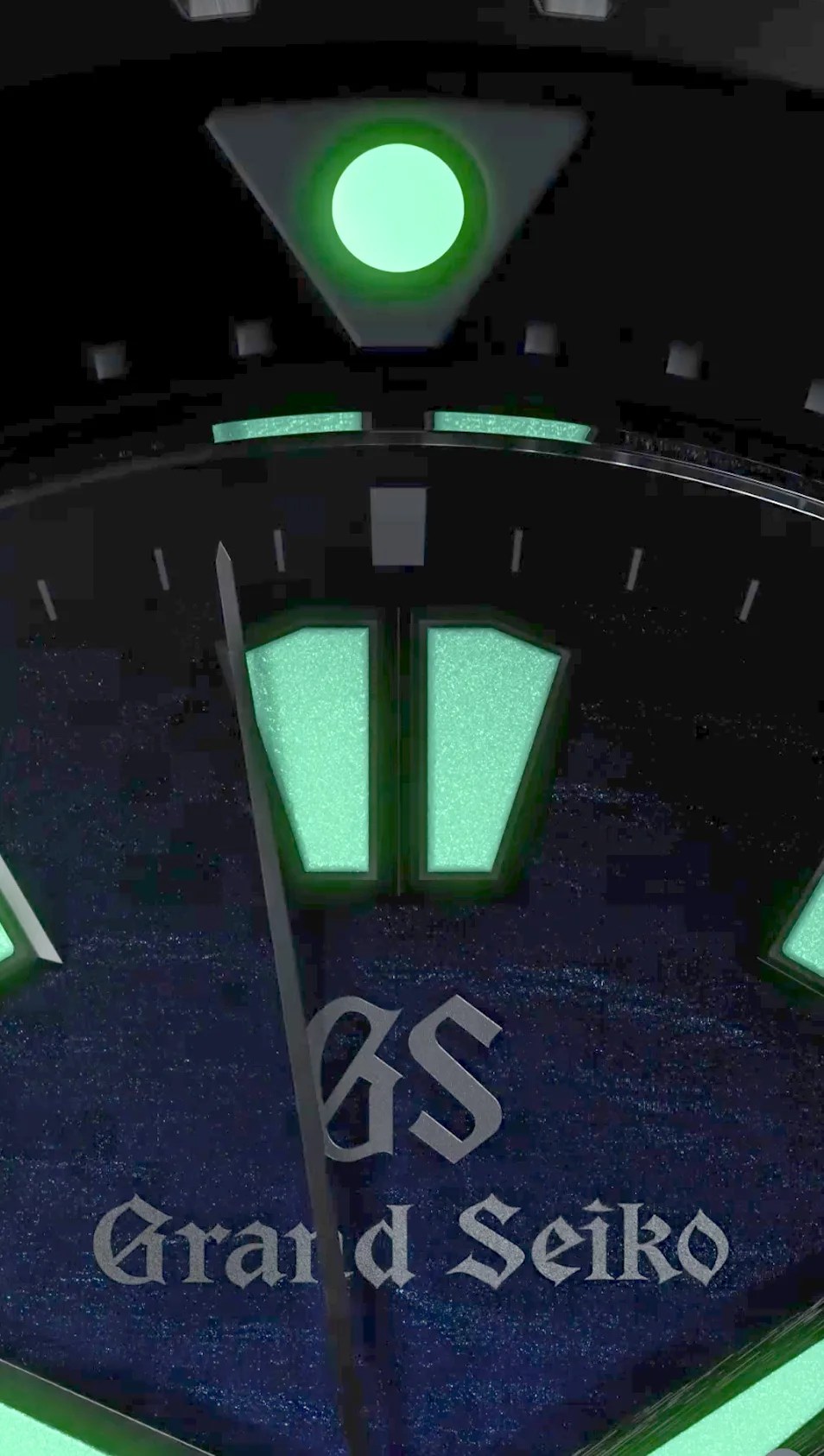 Close-up of a Grand Seiko watch dial showing luminescent green hour markers and hands on a dark textured background.
