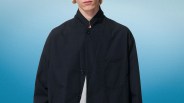 Black button-up jacket with a high collar and a chest pocket worn over a light gray shirt.