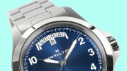 Close-up of a Hamilton wristwatch with a blue dial, white numerals, day and date display, and stainless steel bracelet.