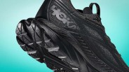 Black Hoka running shoe with textured sole and mesh upper against a teal gradient background.