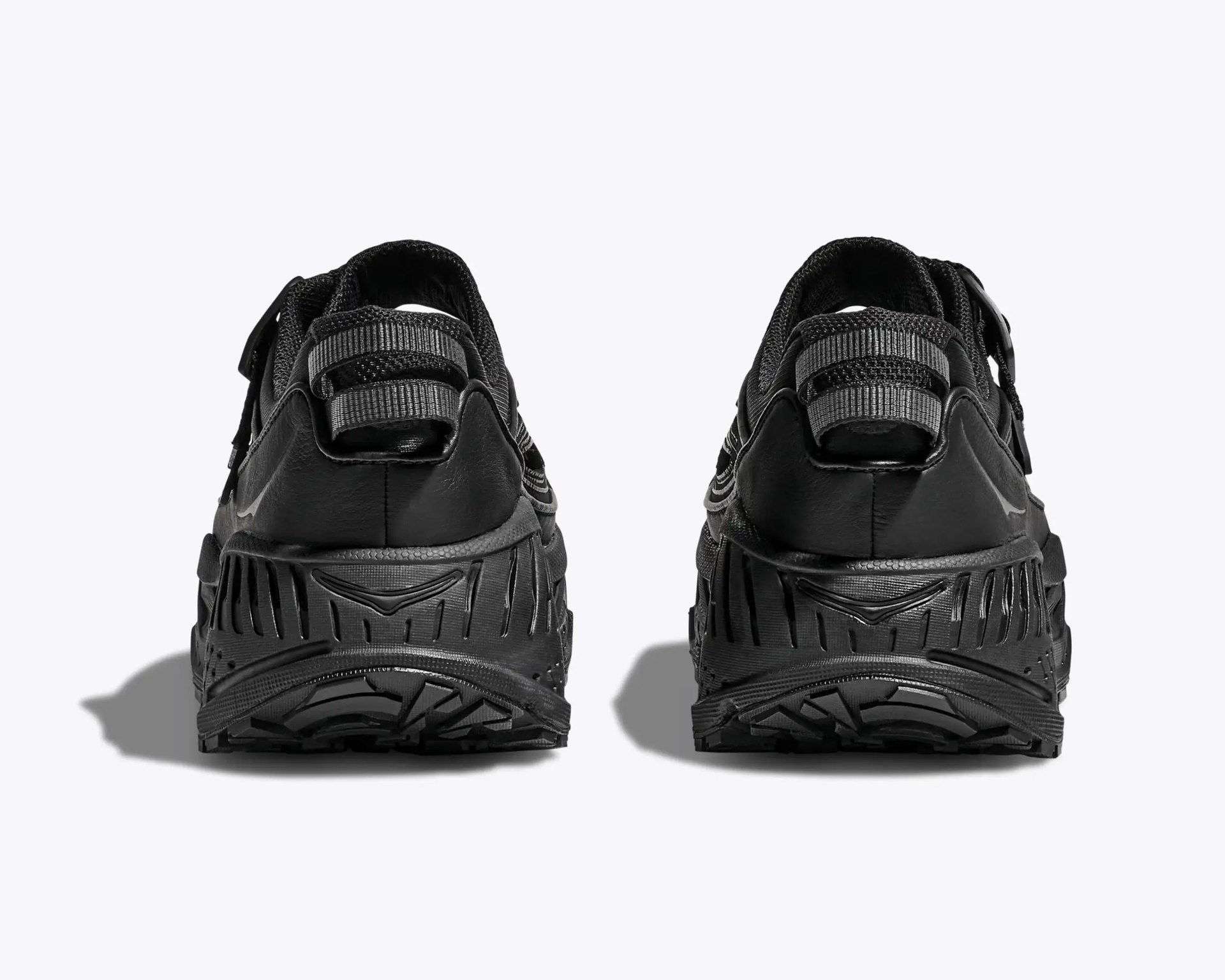 Pair of black athletic shoes with textured soles and pull tabs on the heels, viewed from the back.