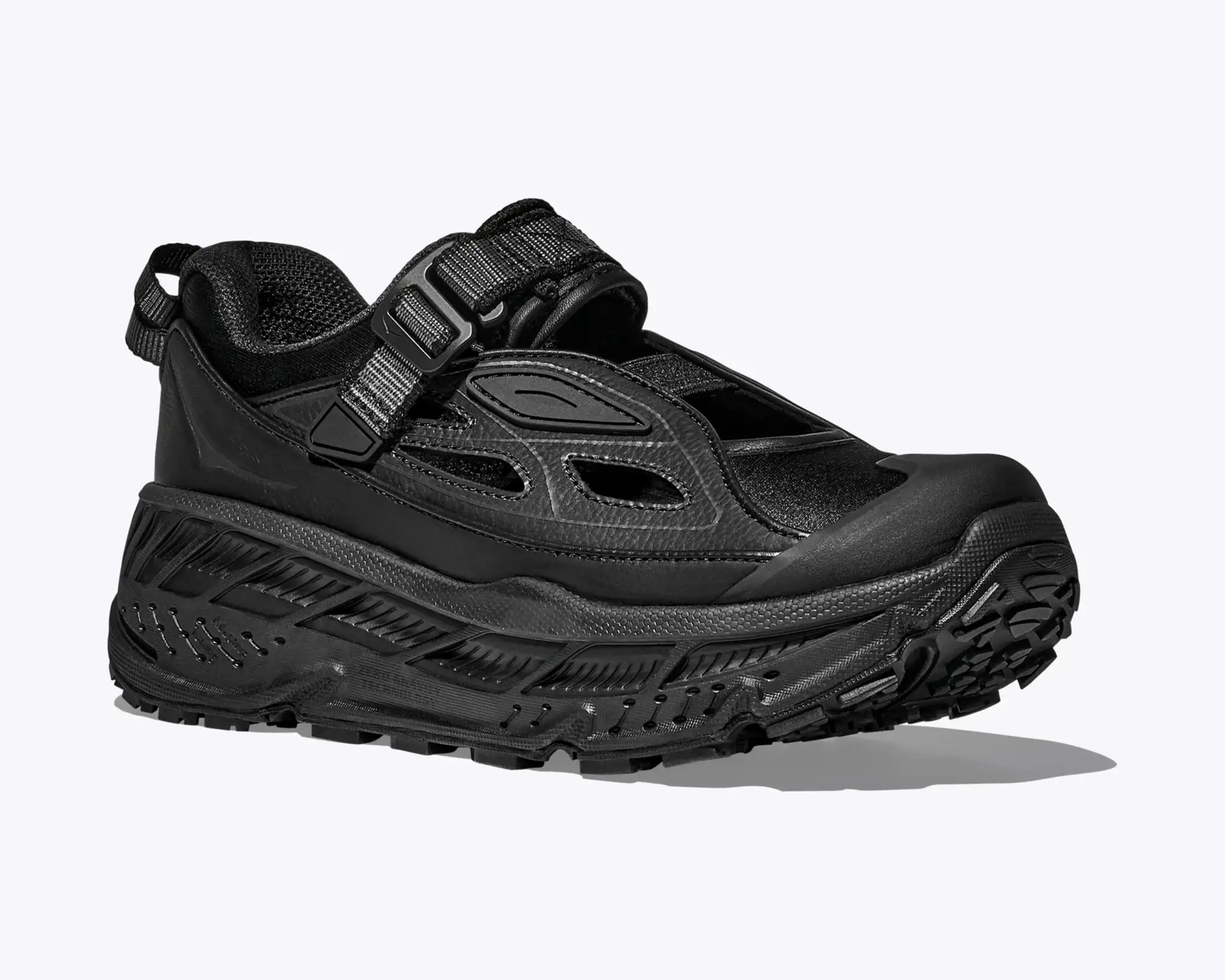 Chunky black athletic shoe with mesh upper, adjustable strap, and thick textured sole.