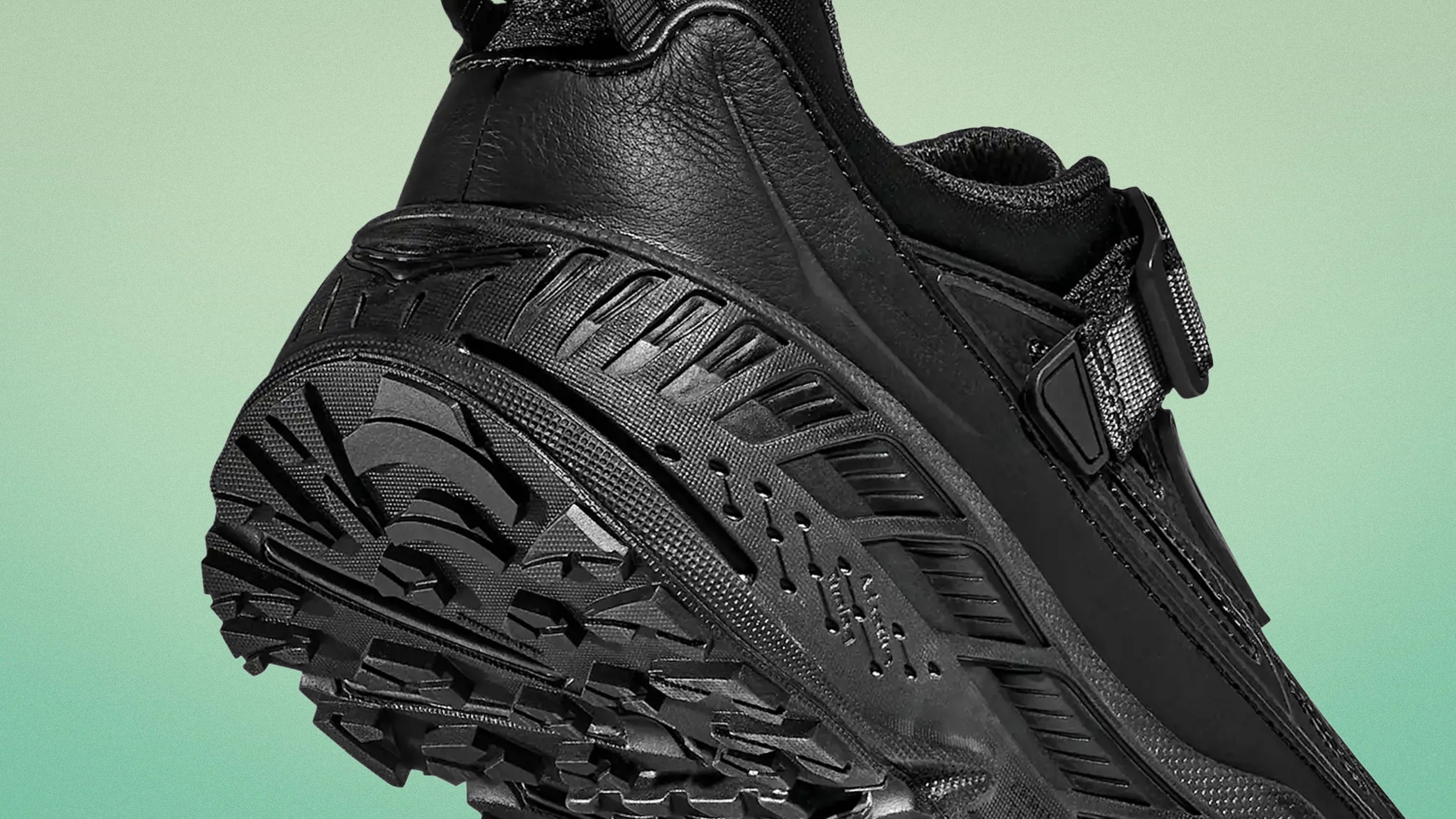 Close-up of the black rugged sole and heel of a trail running shoe with textured grip and synthetic upper.