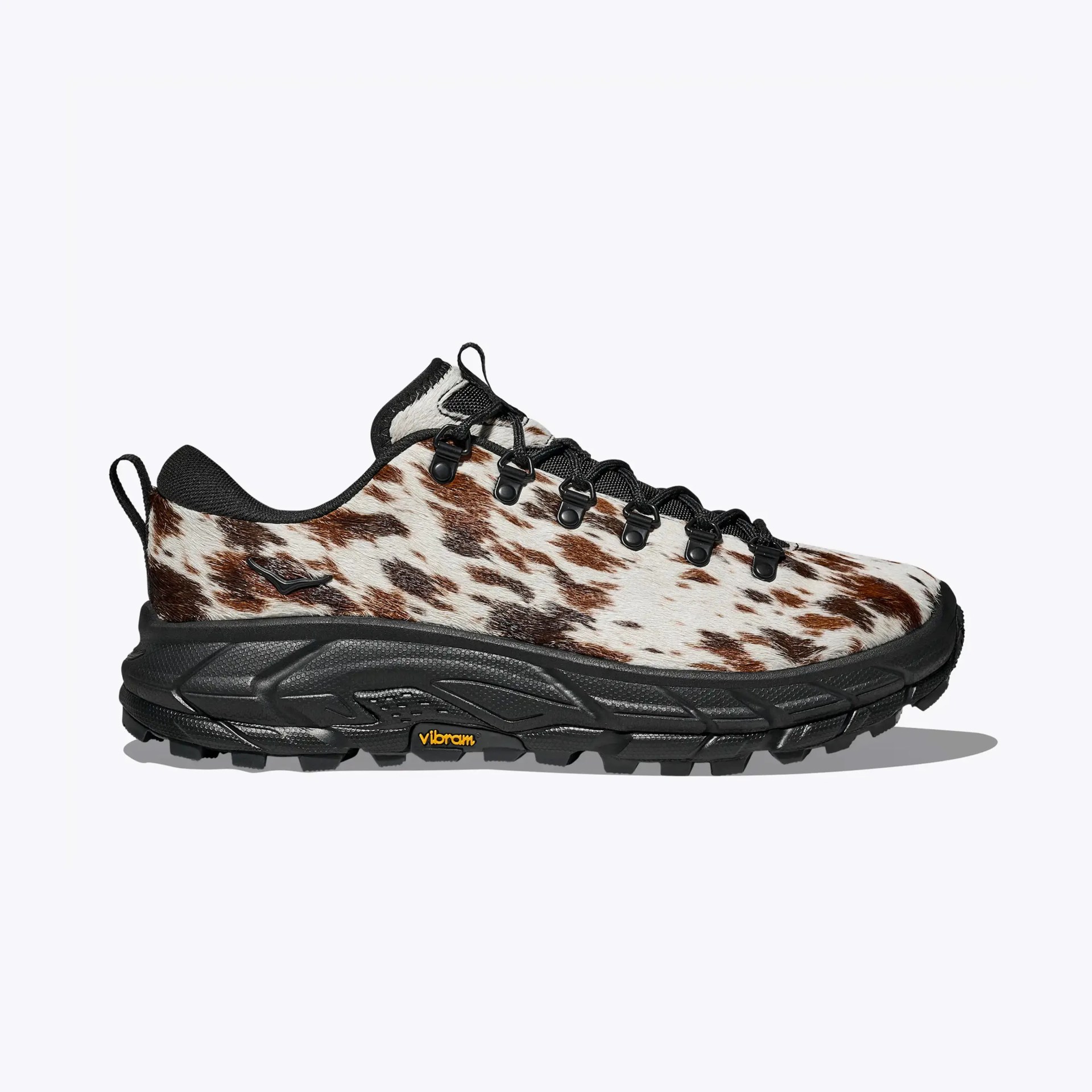 Low-cut hiking shoe with brown and white spotted fur upper and black Vibram sole.
