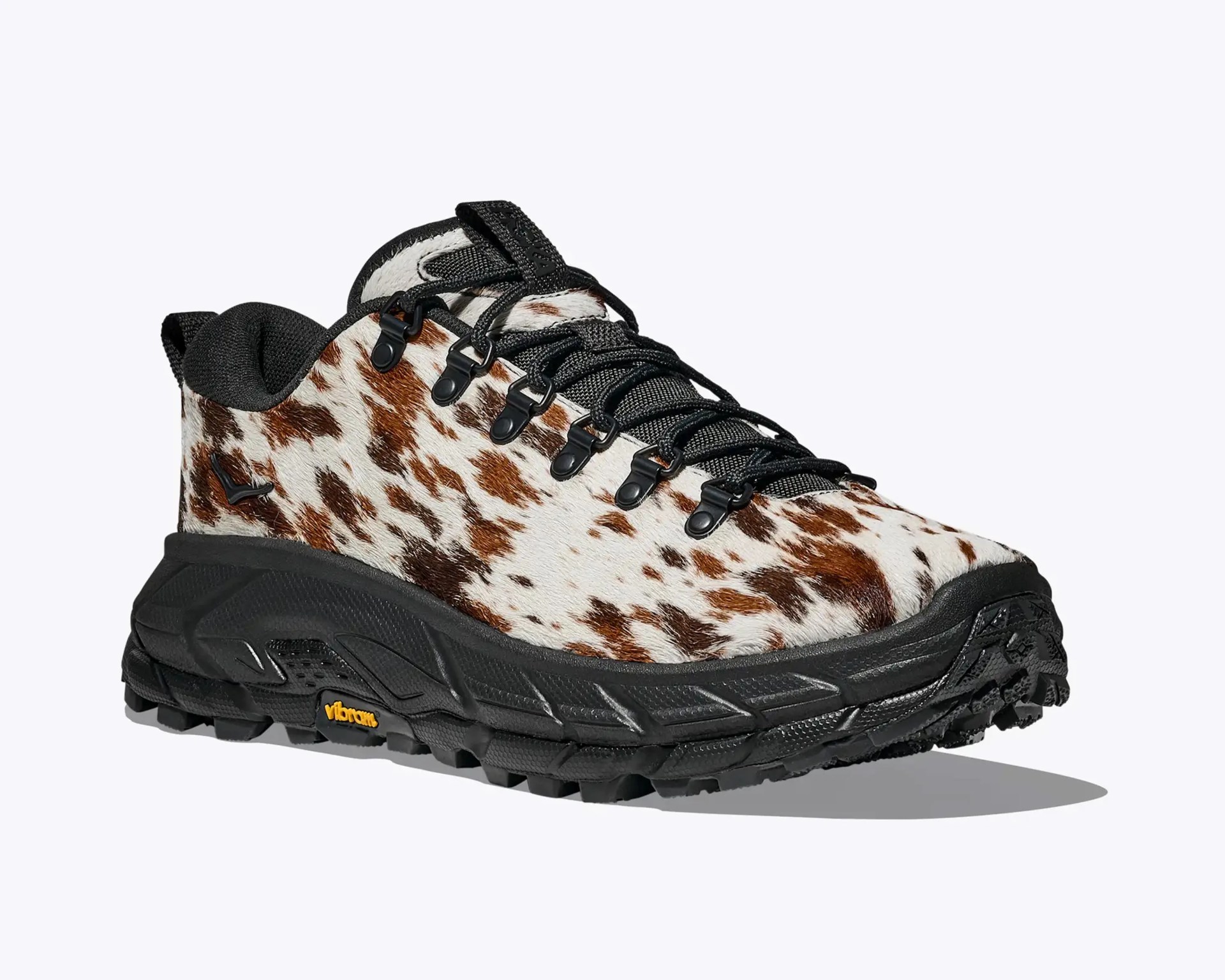 Low-cut hiking shoe with brown and white spotted fur upper and black Vibram sole.