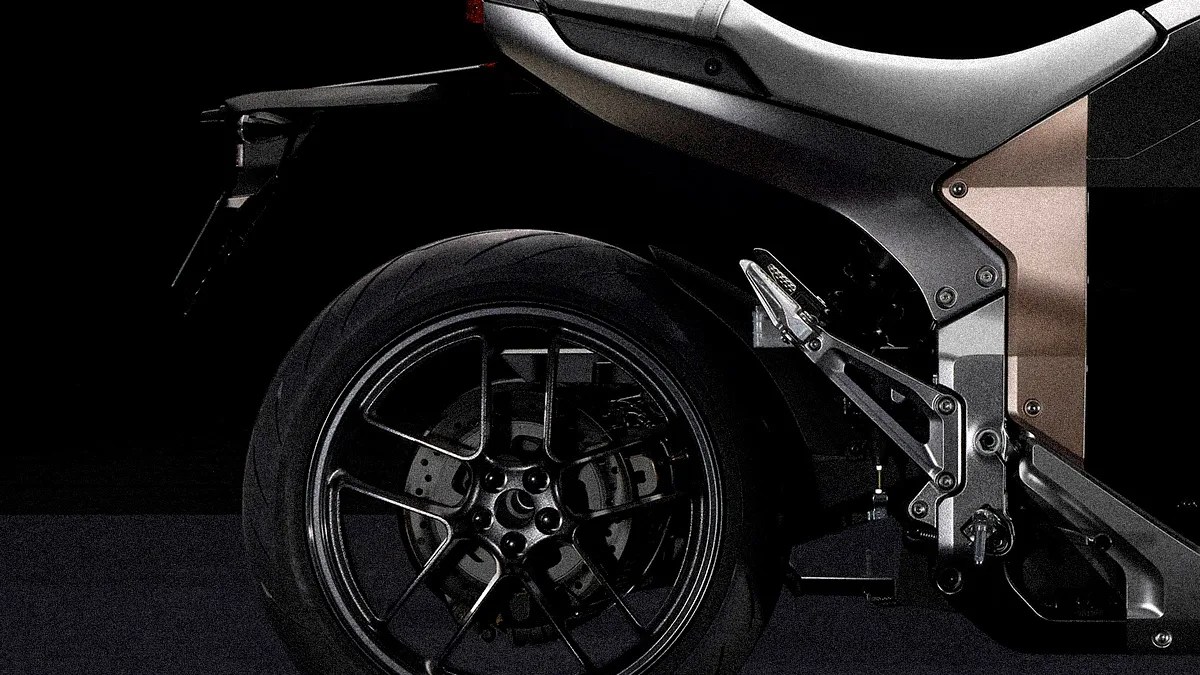 Close-up of a black motorcycle rear wheel with a multi-spoke rim and part of the silver and bronze frame.