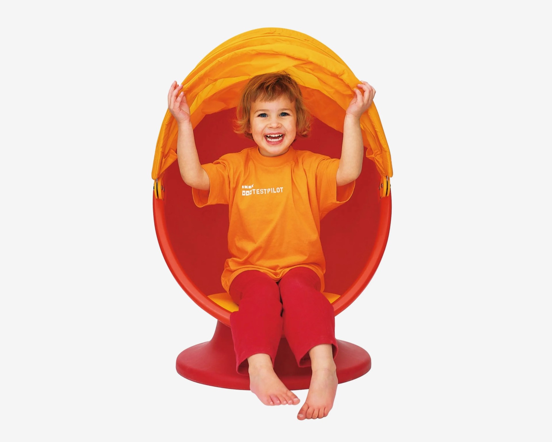 Child in orange T-shirt and red pants sitting in a red and yellow pod chair with a yellow canopy.