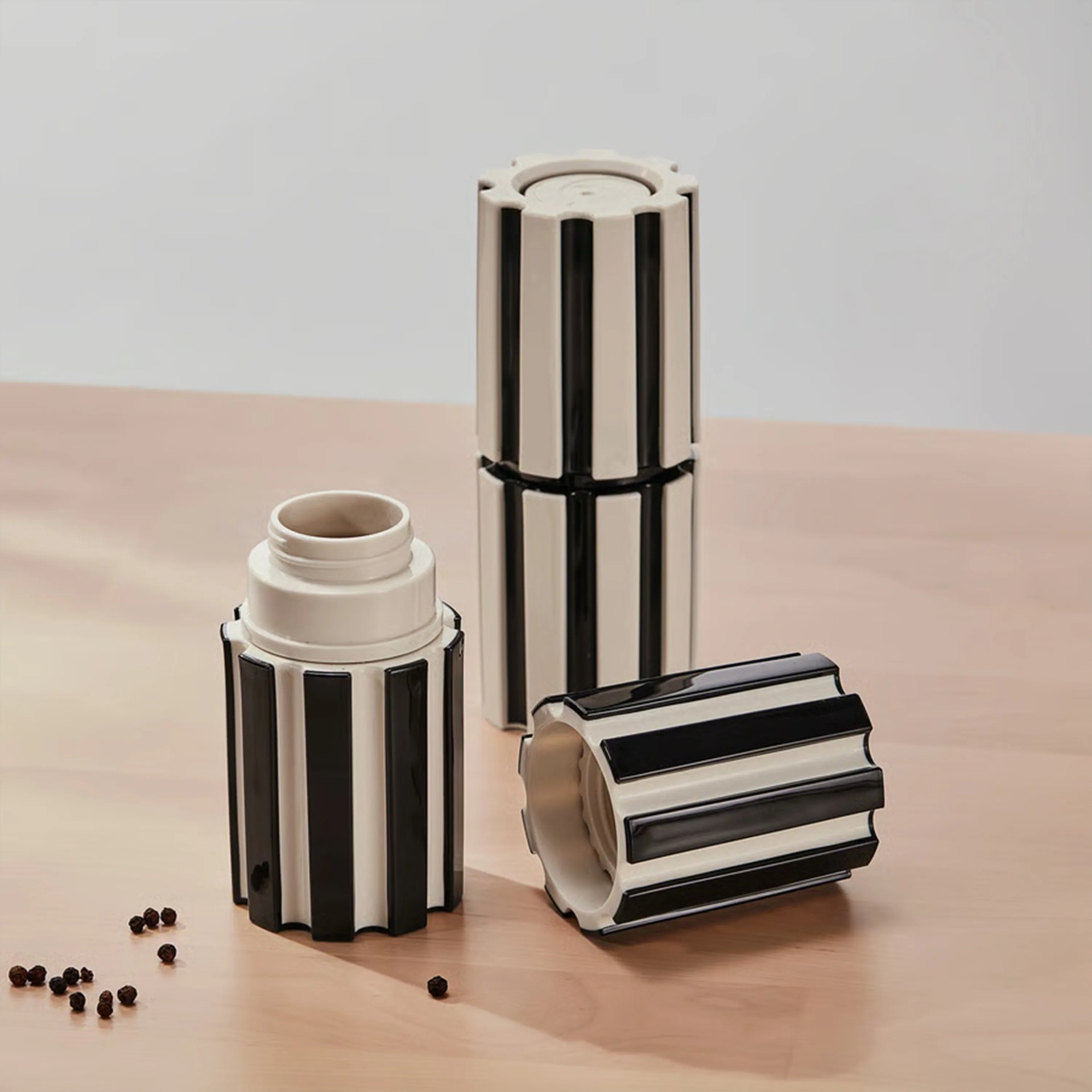 Set of three black and white striped ceramic containers with lids, one open, on a wooden surface.