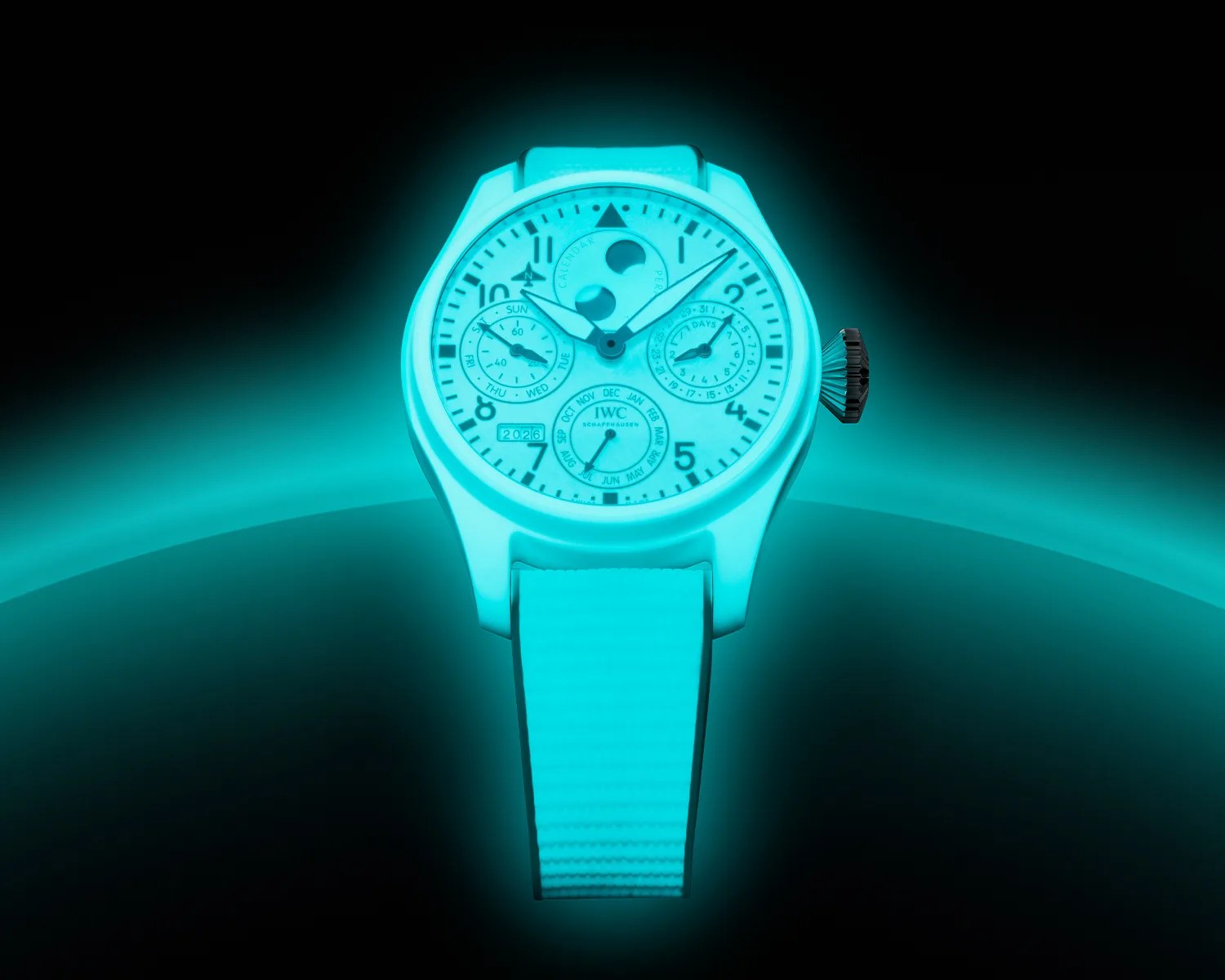 Blue-glowing wristwatch with multiple dials and a textured strap against a dark background.