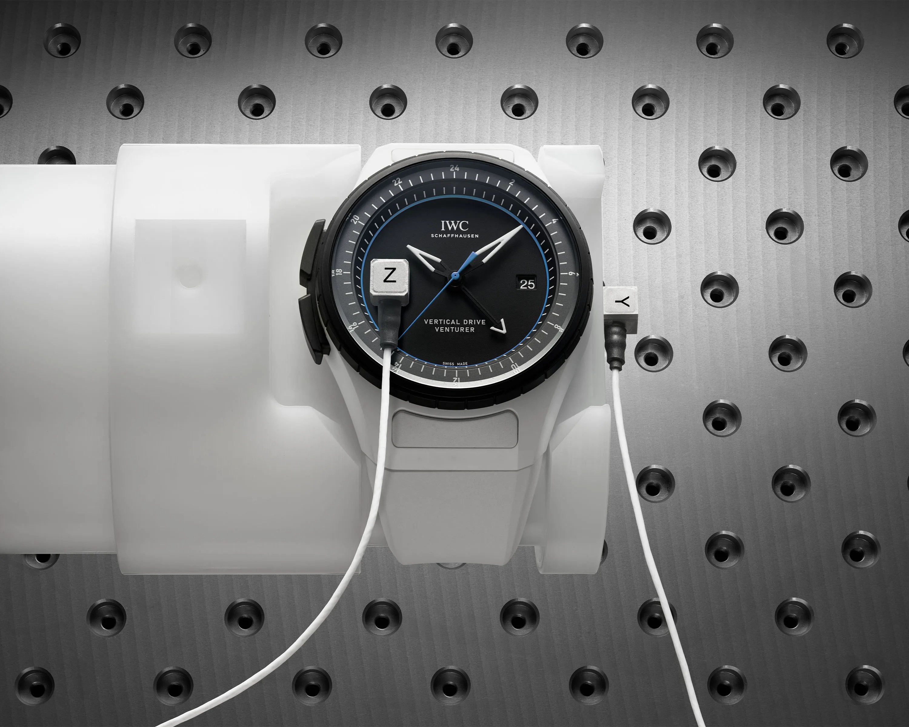 Black dial IWC Schaffhausen Vertical Drive Venturer watch with white strap on a white wrist model against a perforated metal background.