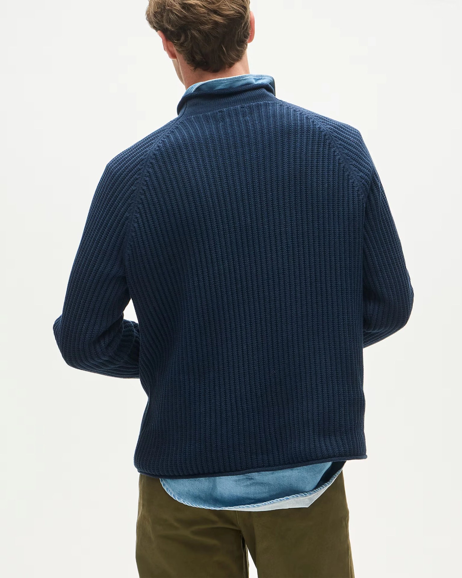 Navy blue textured knit sweater worn over a light blue shirt and olive green pants, viewed from the back.