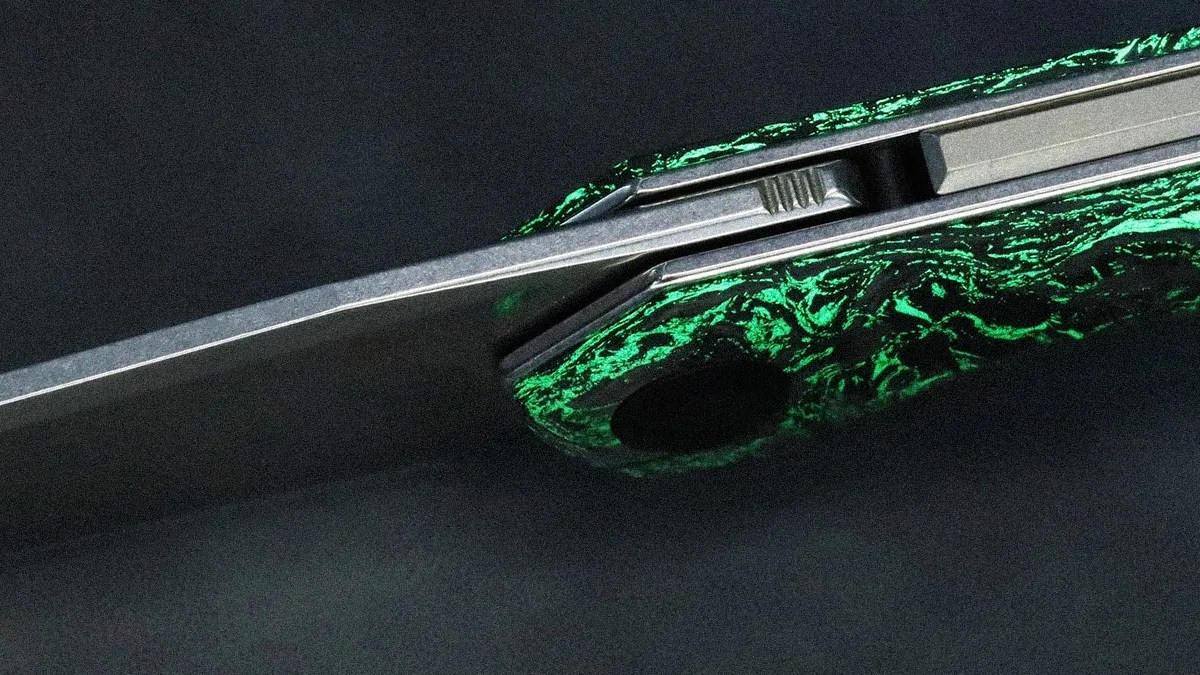 Close-up of a folding knife with a textured green and black handle and a partially visible blade.