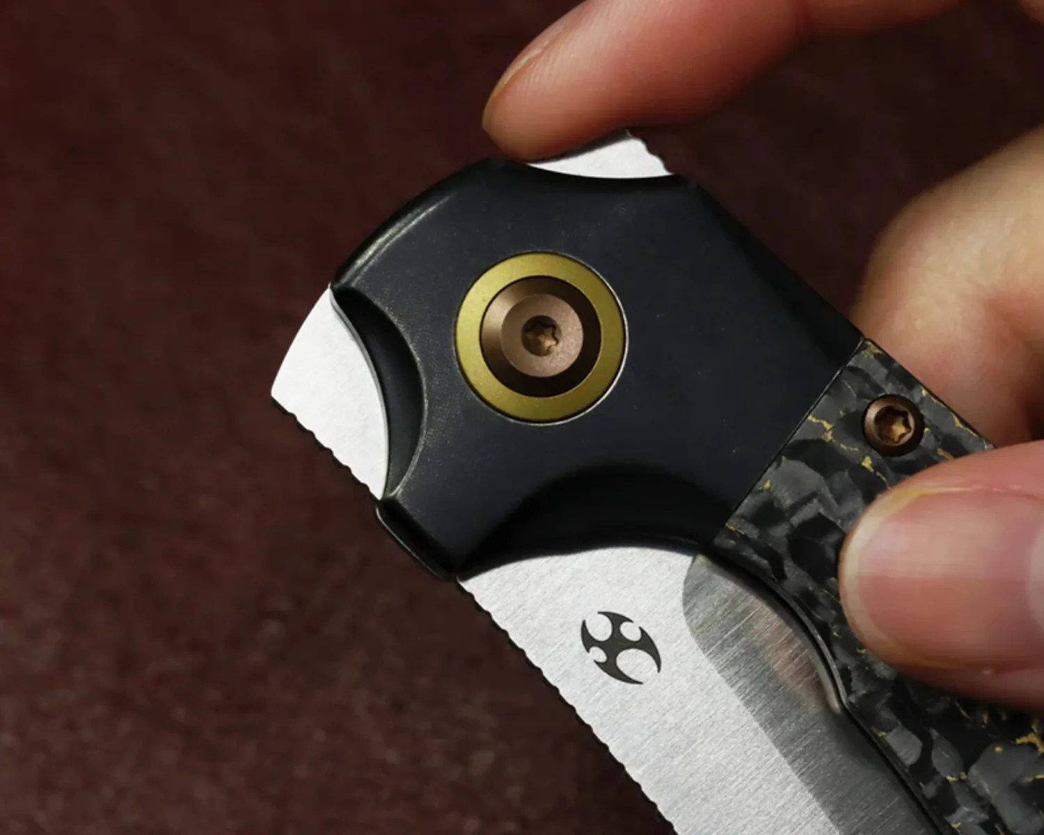 Close-up of a hand holding a folding knife with a partially serrated blade and a black textured handle.