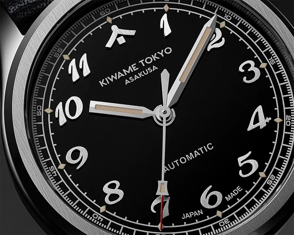 Close-up of a black Kiwame Tokyo Asakusa automatic watch face with silver numerals and hands, and a red-tipped second hand.