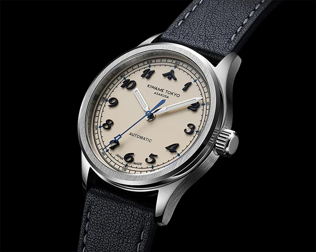 Silver stainless steel wristwatch with cream dial, black Arabic numerals, blue second hand, and black leather strap.