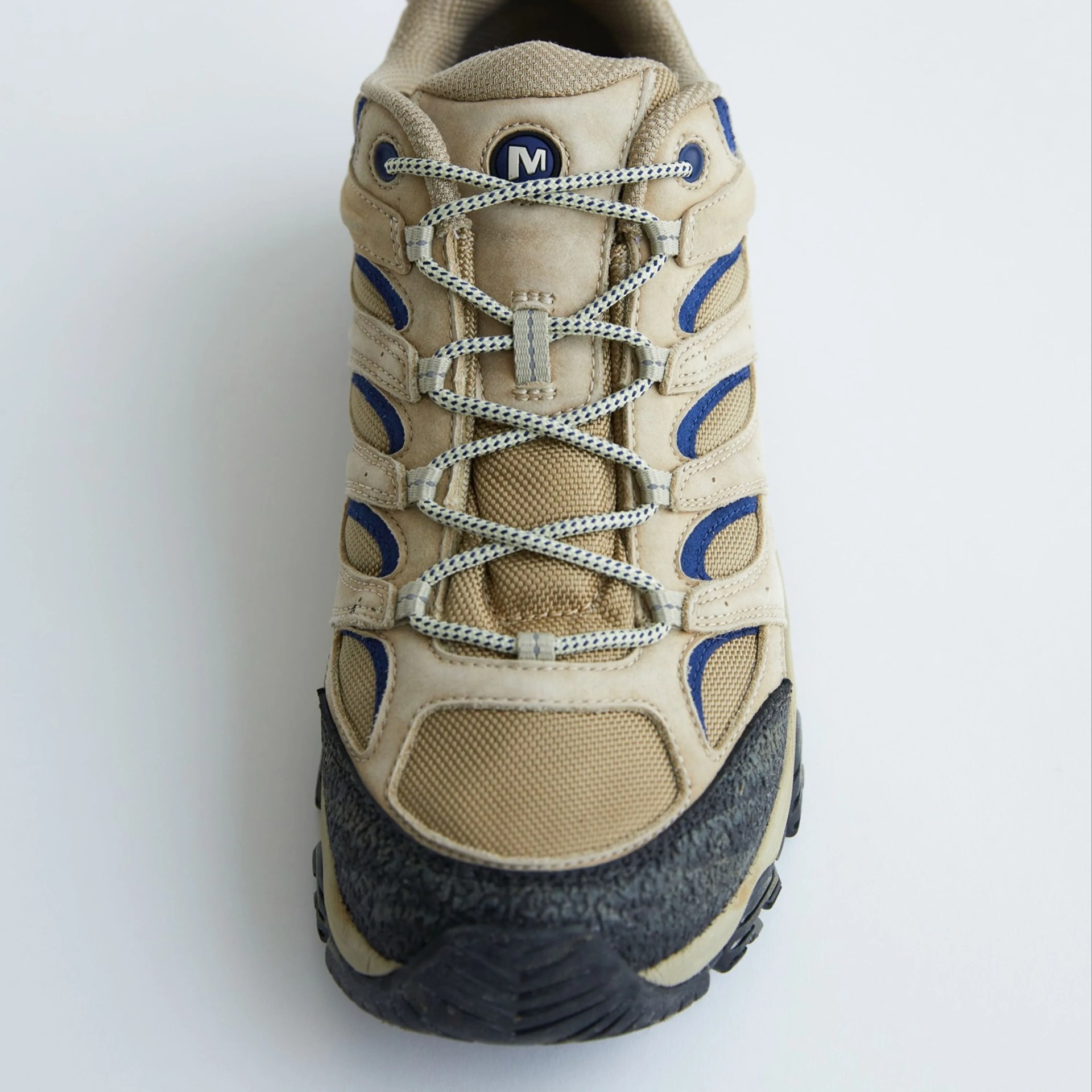 Beige and blue hiking shoe with black textured toe cap and patterned laces on a white background.