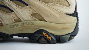 Close-up of beige Merrell hiking shoe with Vibram black sole and orange logo.