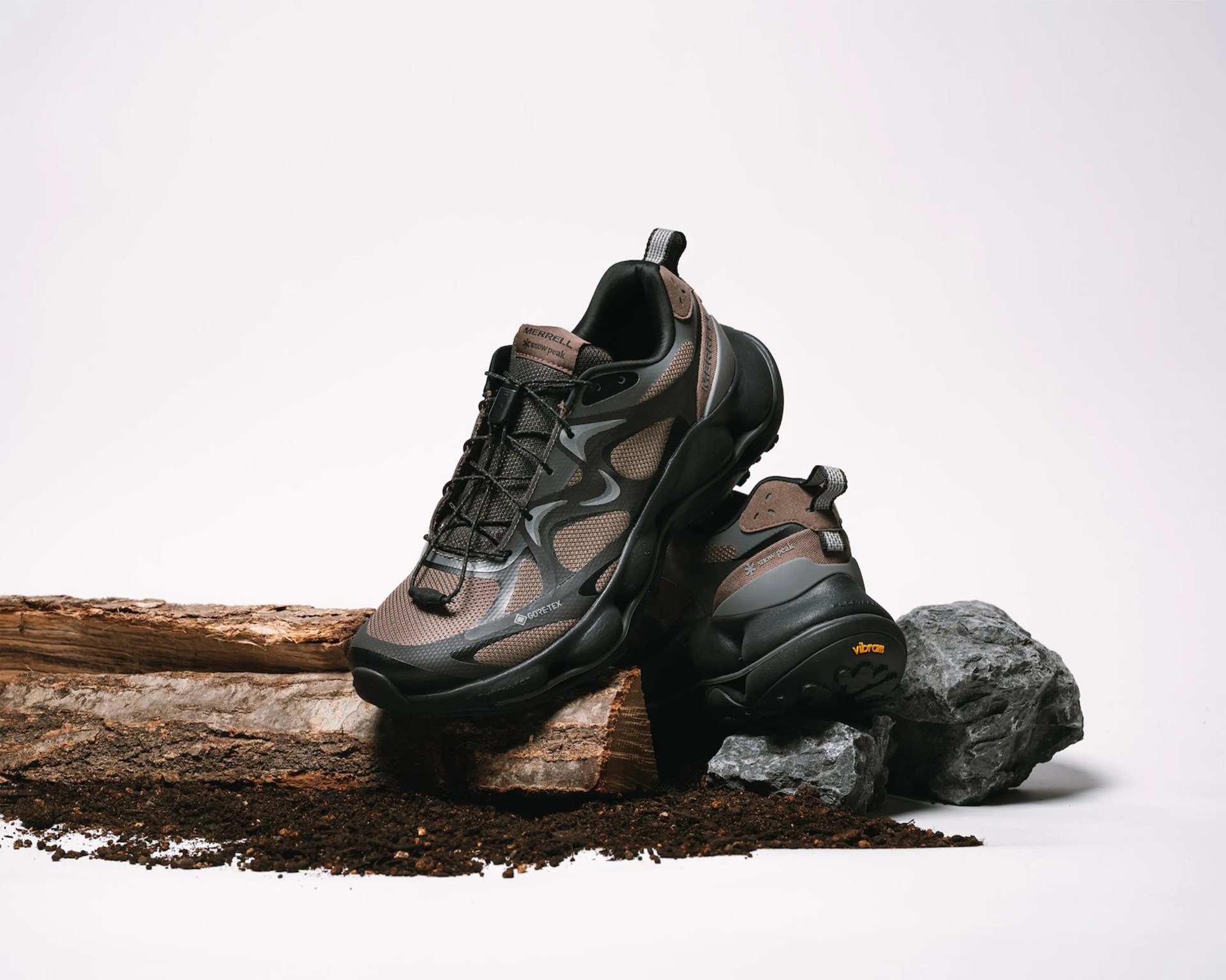 Pair of brown and black Merrell Gore-Tex hiking shoes with Vibram soles on wood and rocks.