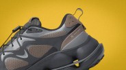 Chunky sneaker in black and brown mesh with pull tab and toggle laces on a yellow background.