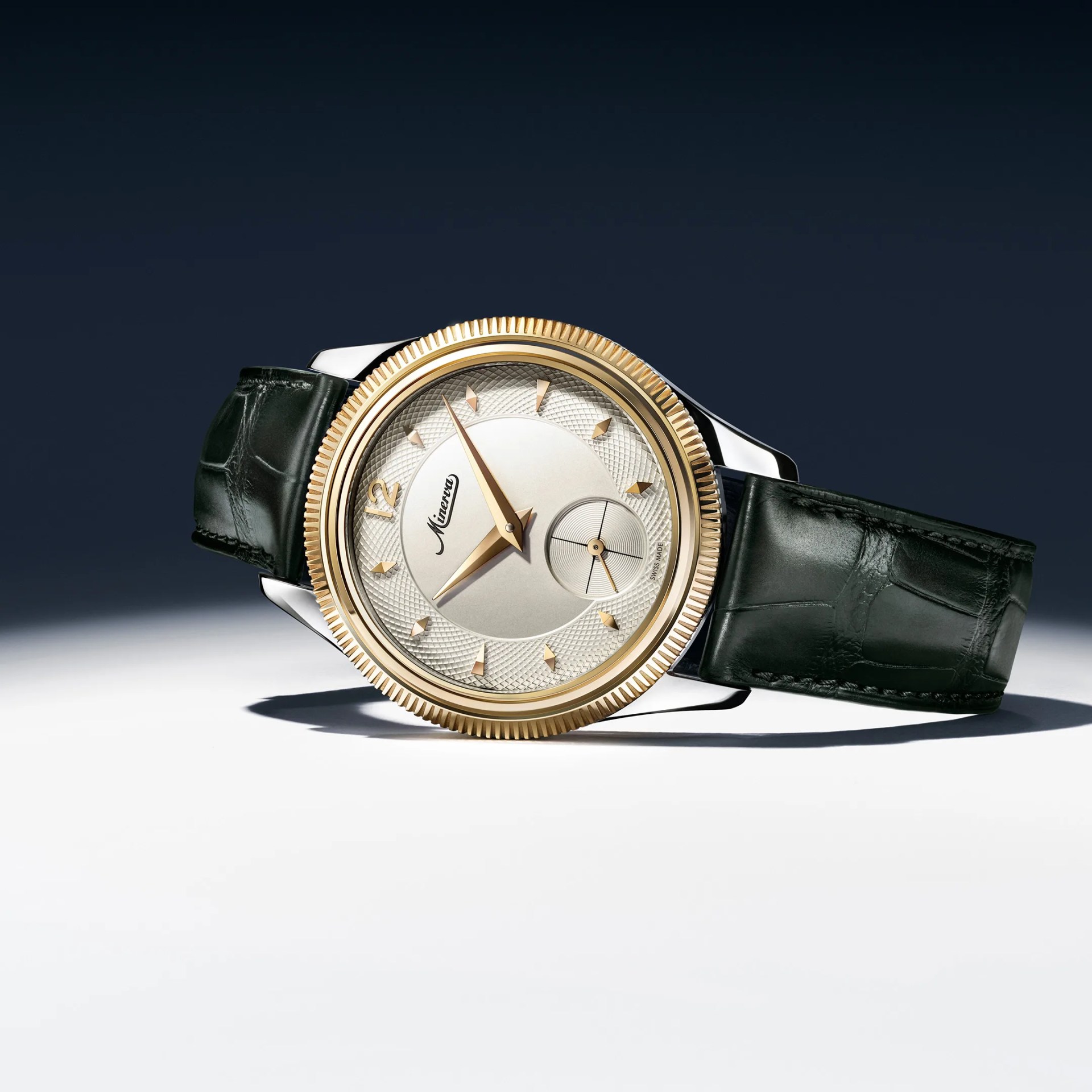Round wristwatch with gold bezel, textured silver dial, gold markers, and black leather strap on a white surface.