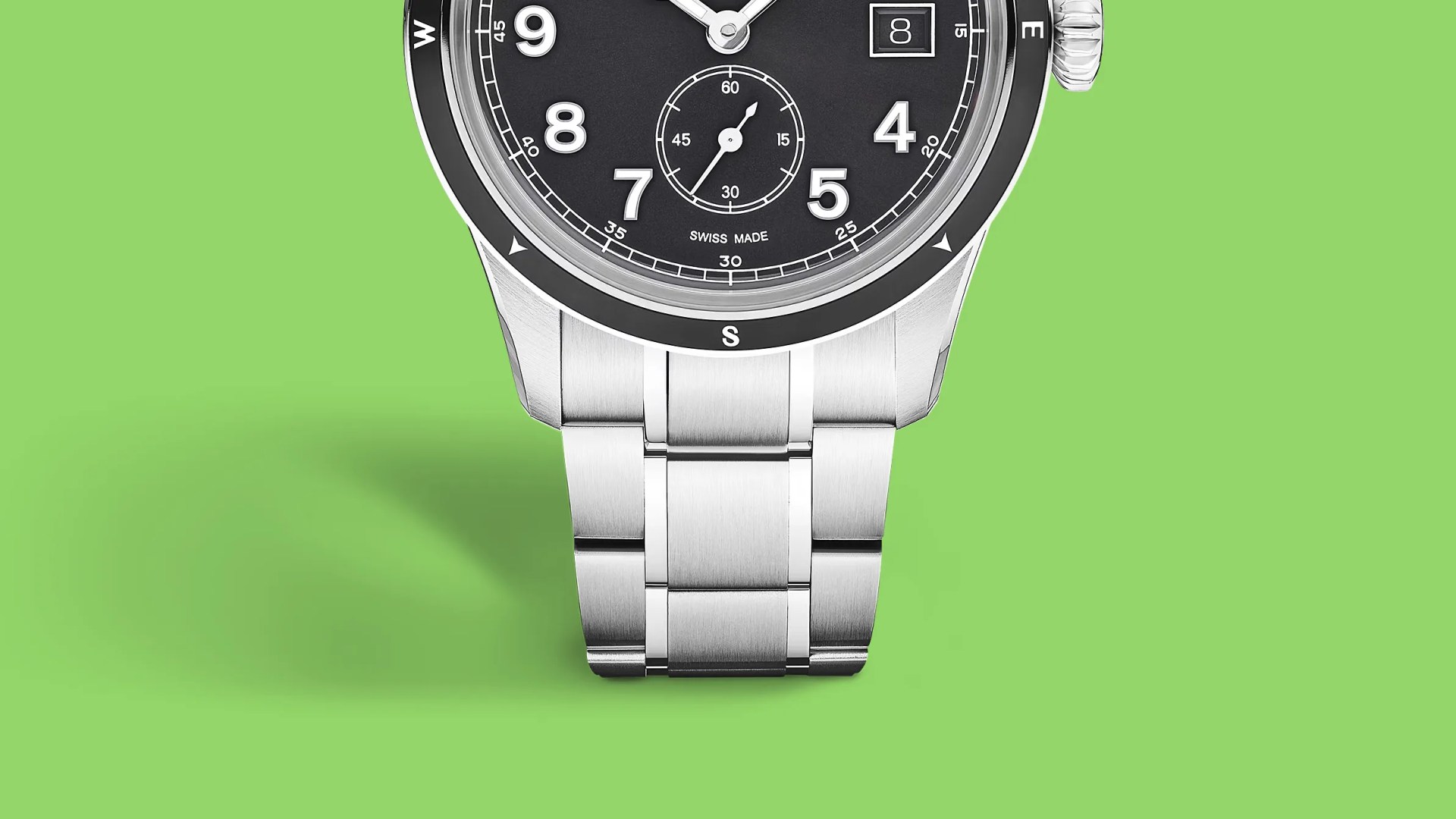 Close-up of a silver metal watch bracelet attached to a black dial watch with white numerals on a green background.