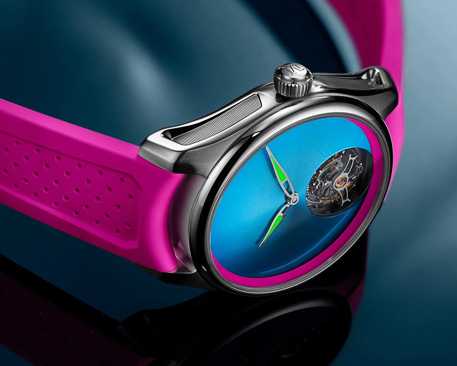 Close-up of a wristwatch with a blue dial, green-accented hands, visible tourbillon, silver case, and bright pink perforated rubber strap.