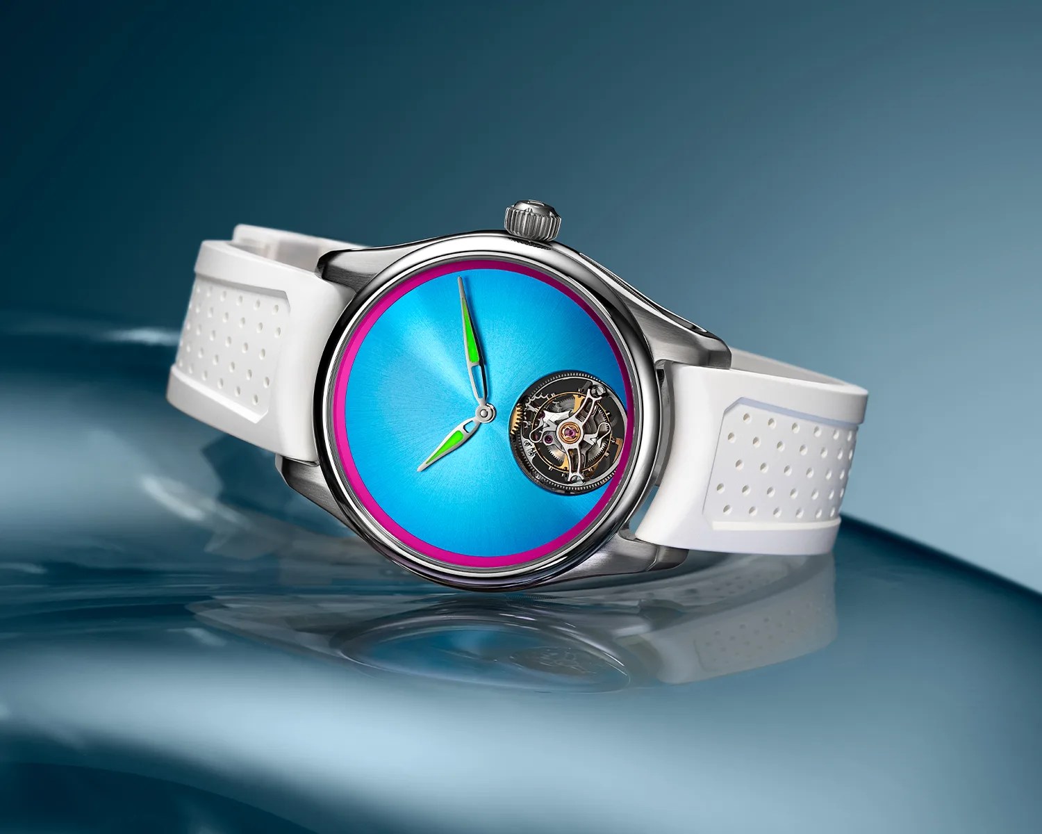 Silver wristwatch with bright blue dial, pink outer ring, green-accented hands, visible tourbillon, and white perforated rubber strap.