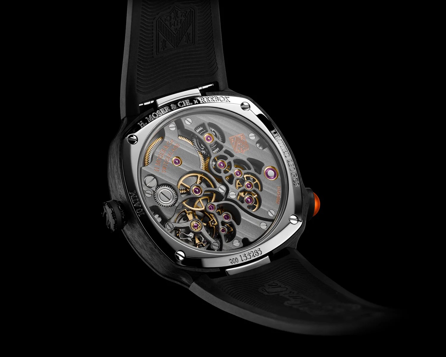 Close-up of the back of a luxury watch showing intricate gold and purple gears inside a polished metal case with a black rubber strap.