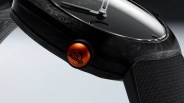 Close-up of a black watch with a textured strap and an orange crown button labeled "THE pump.
