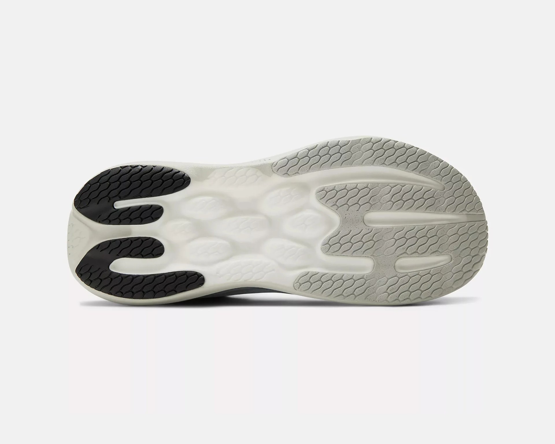 White and black textured rubber outsole of a shoe with hexagonal and oval patterns.