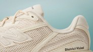Close-up of beige New Balance sneaker with mesh upper and "District Vision" branding on the heel.