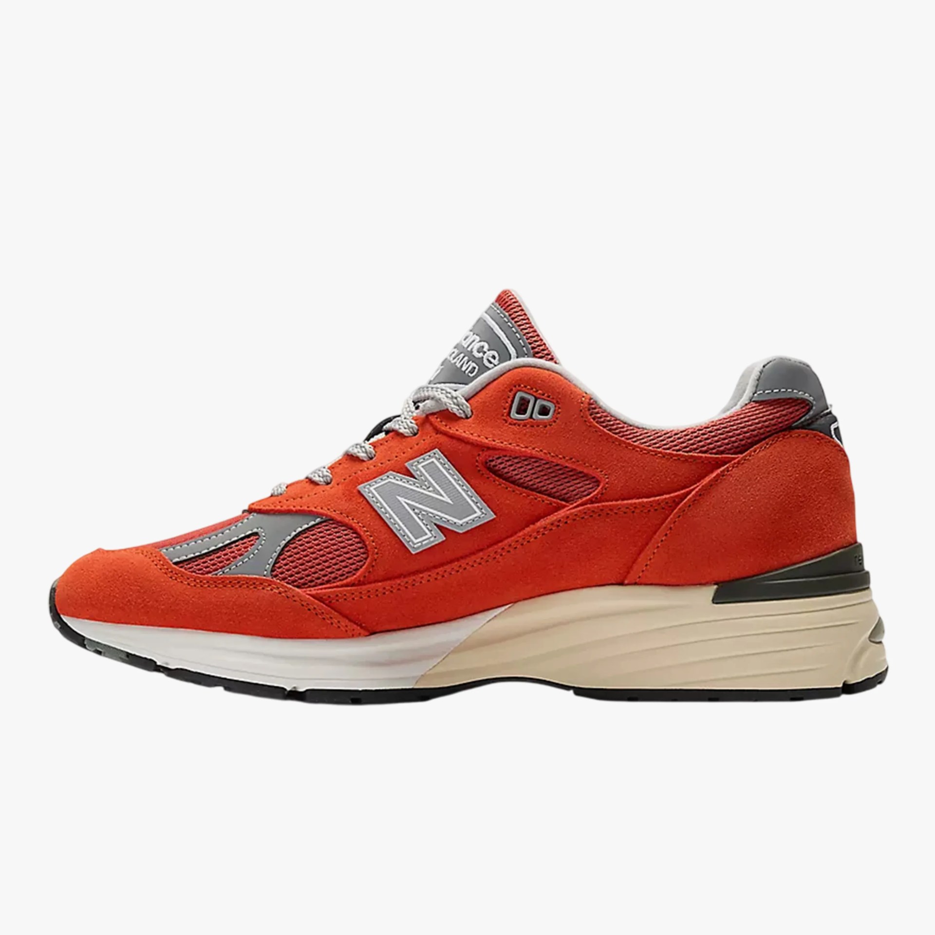 Orange and gray New Balance sneaker with suede and mesh upper and beige cushioned sole.