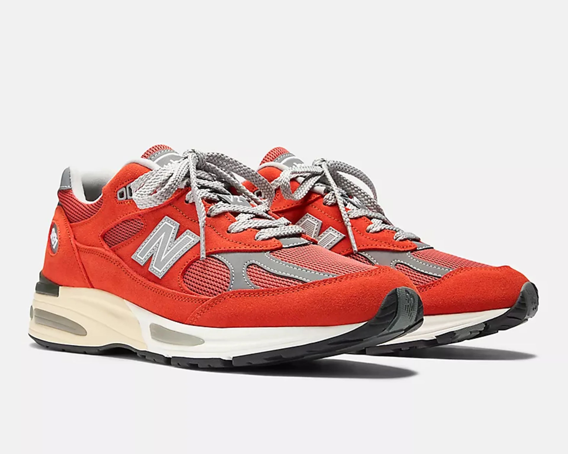 Pair of red and gray New Balance sneakers with white midsoles and black outsoles.