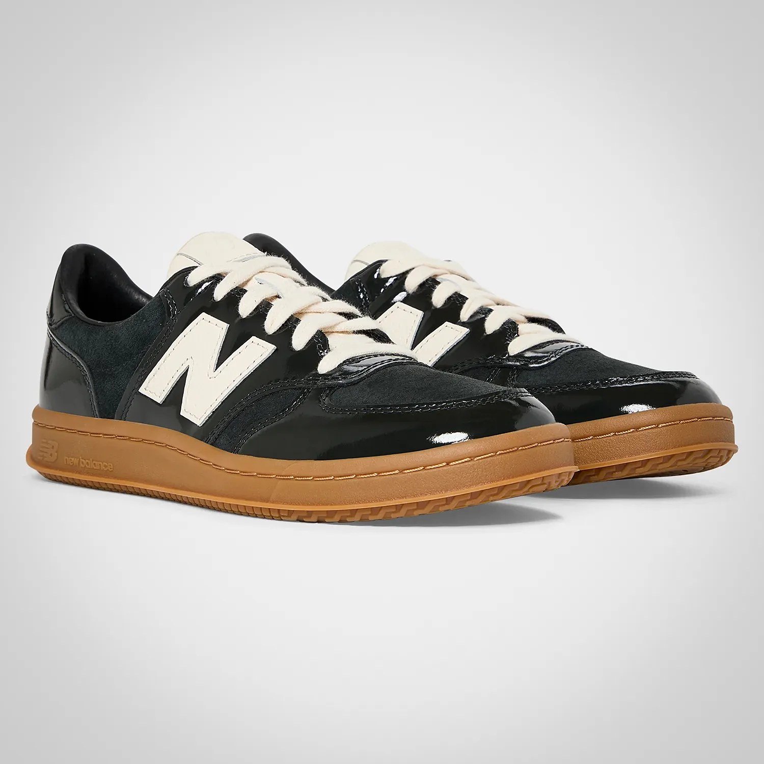 Pair of black New Balance sneakers with white laces and logos, featuring gum rubber soles.