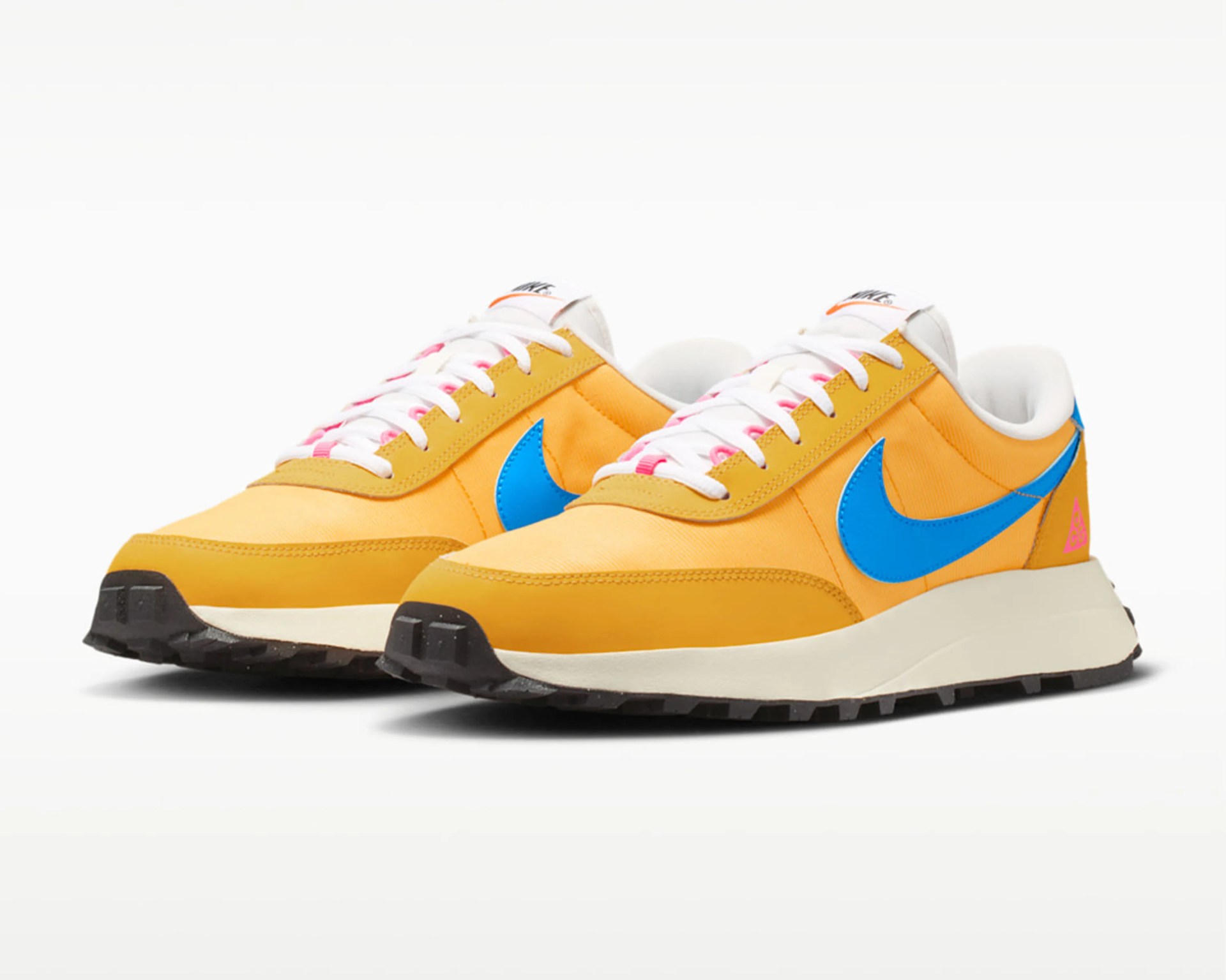 Pair of yellow Nike sneakers with blue swoosh logos, white laces with pink accents, and black soles.